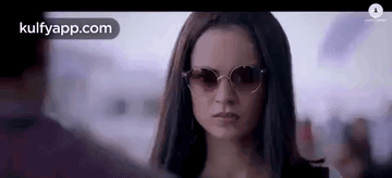 A Close Up Of A Woman Wearing Sunglasses Looking At A Man . GIF