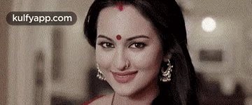 A Close Up Of A Woman With A Red Dot On Her Forehead Smiling . GIF