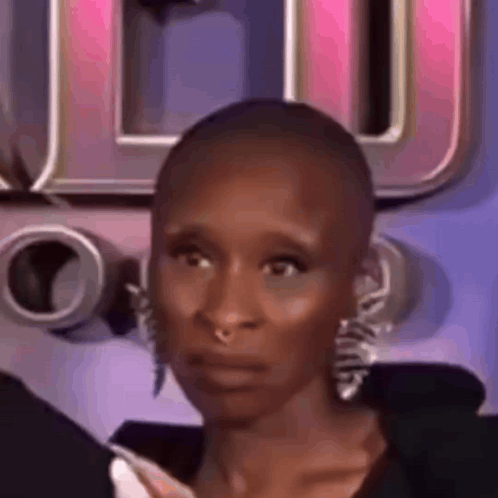 A Close Up Of A Woman With A Shaved Head And Earrings Making A Funny Face . GIF