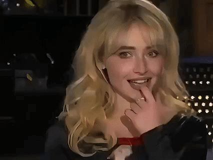 A Close Up Of A Woman With Blonde Hair Covering Her Mouth With Her Hand . GIF