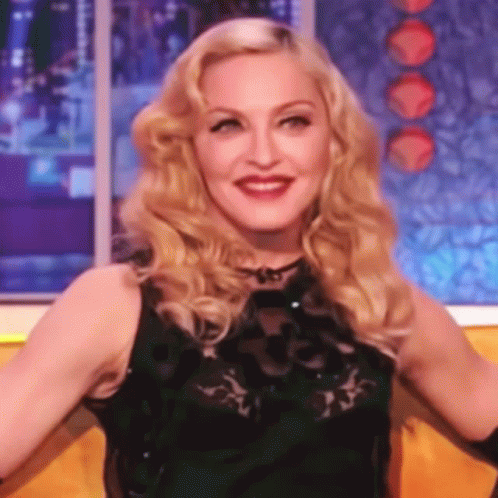 A Close Up Of A Woman With Blonde Hair Wearing A Black Dress GIF