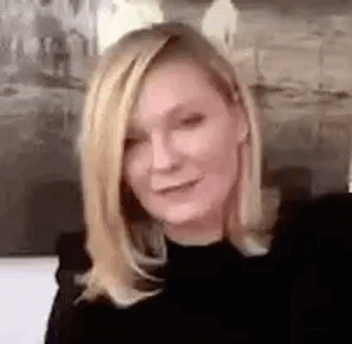 A Close Up Of A Woman With Blonde Hair Wearing A Black Shirt And Smiling . GIF
