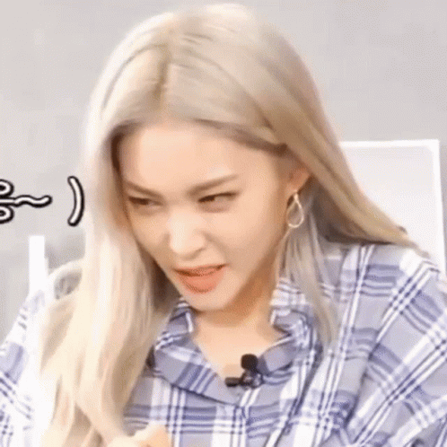 A Close Up Of A Woman With Blonde Hair Wearing A Plaid Shirt And Earrings Making A Funny Face . GIF