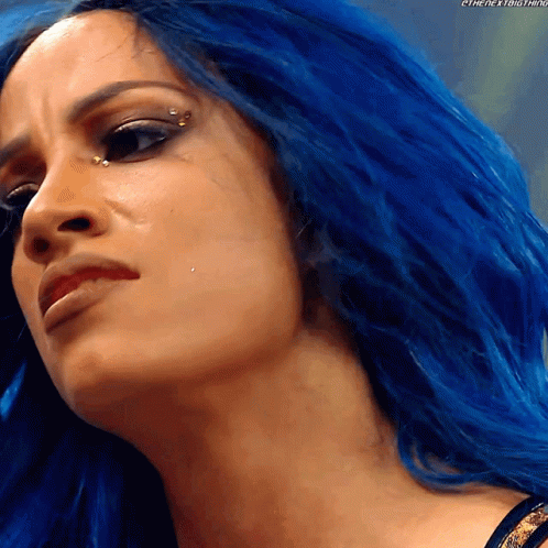 A Close Up Of A Woman With Blue Hair And A Piercing In Her Eye GIF