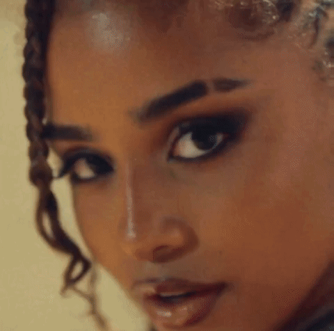 A Close Up Of A Woman With Braids And Hoop Earrings GIF