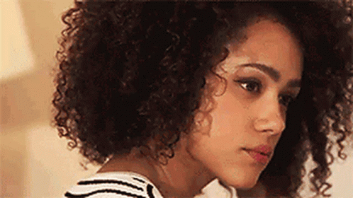 A Close Up Of A Woman With Curly Hair And A Striped Shirt . GIF
