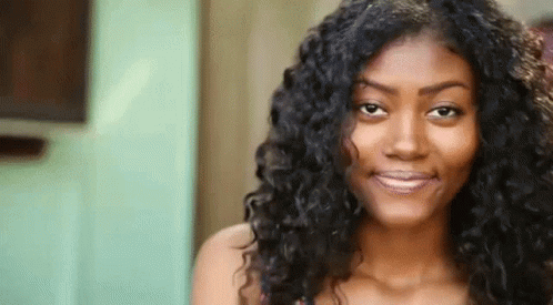 A Close Up Of A Woman With Curly Hair Smiling . GIF