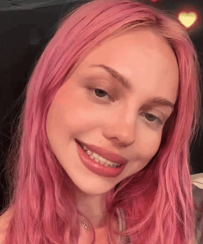 a close up of a woman with pink hair smiling