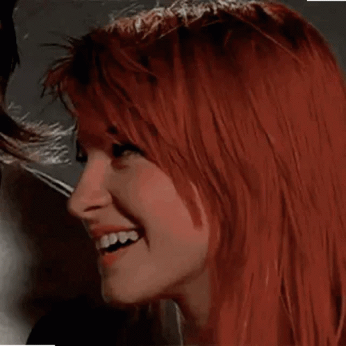 A Close Up Of A Woman With Red Hair Smiling And Looking At The Camera . GIF