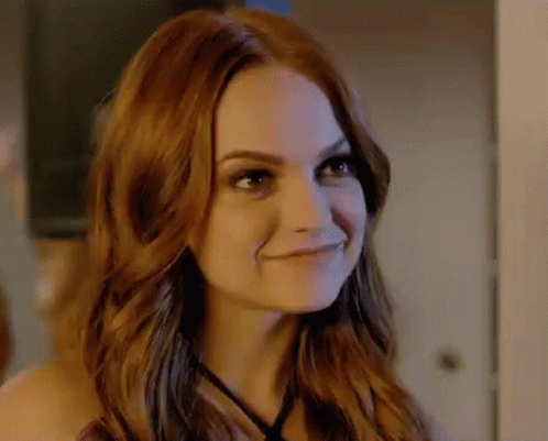 A Close Up Of A Woman With Red Hair Smiling In A Room . GIF