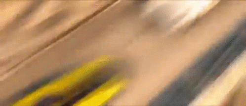 A Close Up Of A Yellow Car Driving Down A Wooden Road . GIF