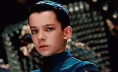 A Close Up Of A Young Boy Wearing A Blue Jacket And Turtleneck . GIF