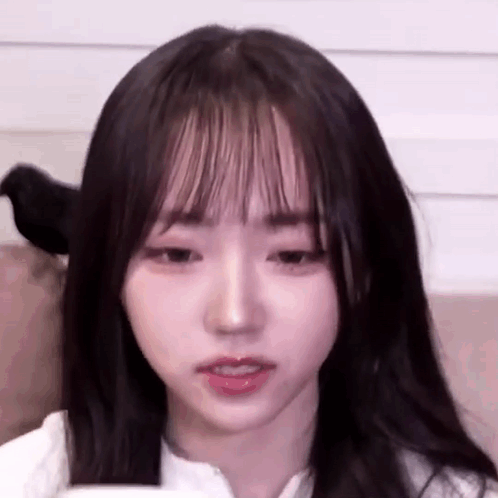 A Close Up Of A Young Girl With Long Hair And Bangs Looking At The Camera . GIF
