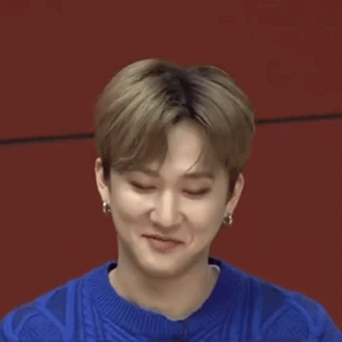 A Close Up Of A Young Man Making A Funny Face While Wearing A Blue Sweater And Earrings . GIF