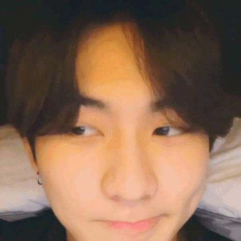 A Close Up Of A Young Man 'S Face Making A Funny Face While Laying On A Bed . GIF