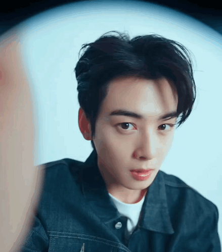 A Close Up Of A Young Man 'S Face Wearing A Denim Jacket GIF