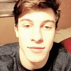 A Close Up Of A Young Man 'S Face Wearing A Grey Shirt . GIF