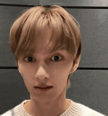 A Close Up Of A Young Man 'S Face Wearing A White Sweater And Making A Funny Face . GIF