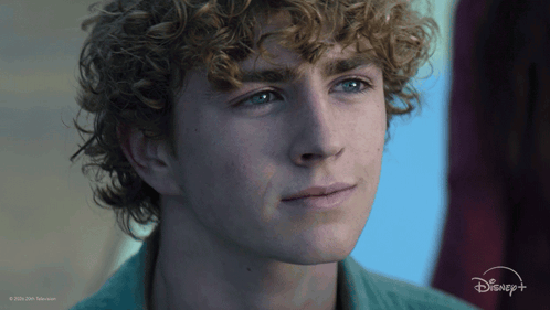 A Close Up Of A Young Man 'S Face With A Disney Logo In The Background GIF