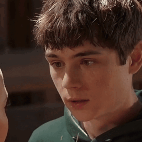 A Close Up Of A Young Man 'S Face With A Green Sweatshirt On GIF