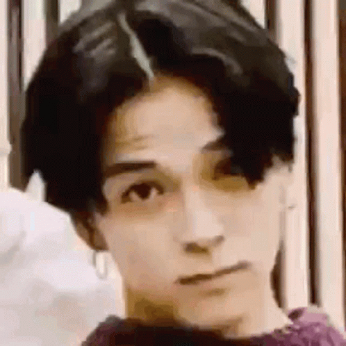 A Close Up Of A Young Man 'S Face With A Purple Shirt On . GIF