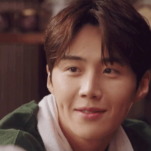 A Close Up Of A Young Man 'S Face With A Towel Around His Neck And A Green Jacket . GIF