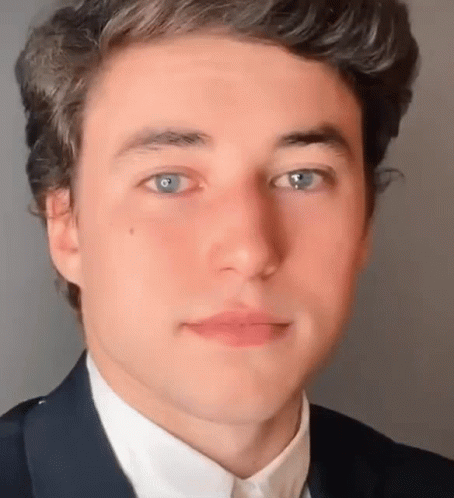 A Close Up Of A Young Man 'S Face With Blue Eyes Wearing A Suit And White Shirt . GIF