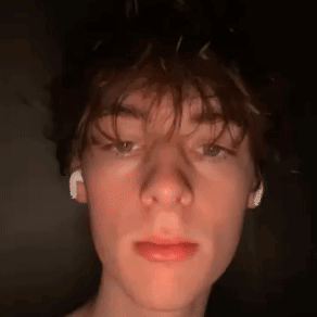 A Close Up Of A Young Man 'S Face With Ear Buds In His Ears . GIF