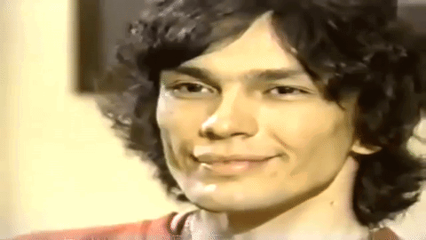 A Close Up Of A Young Man With Curly Hair Smiling . GIF