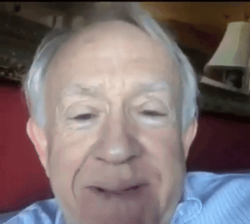 A Close Up Of An Older Man 'S Face With A Lamp Behind Him GIF