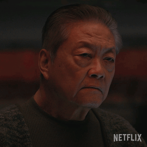 A Close Up Of An Older Man 'S Face With A Netflix Logo Behind Him GIF