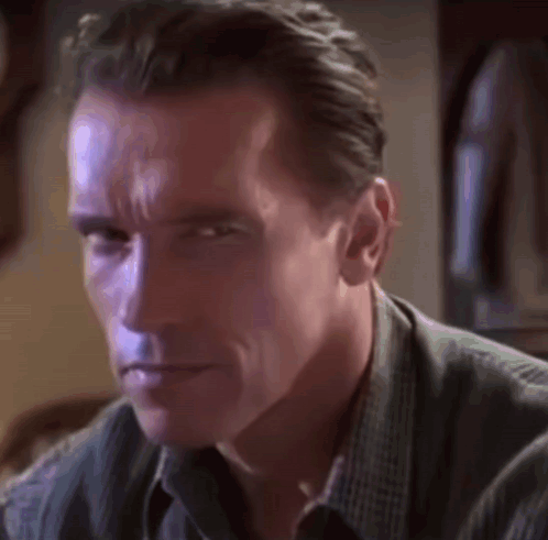 A Close Up Of Arnold Schwarzenegger 'S Face In A Dark Room GIF