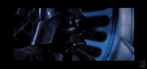 A Close Up Of Darth Vader 'S Face With A Blue Light Coming Out Of His Mouth . GIF