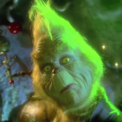 A Close Up Of Grinch 'S Face With Green Hair And Yellow Eyes GIF