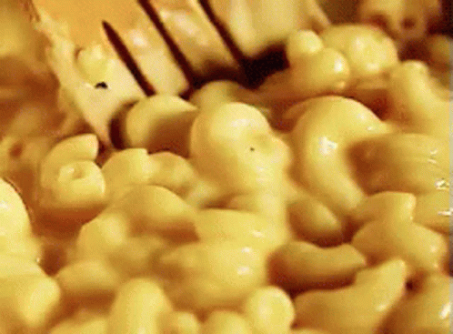 A Close Up Of Macaroni And Cheese Being Stirred With A Fork GIF