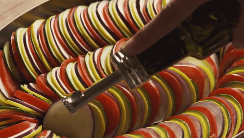 A Close Up Of Sliced Vegetables With A Bottle Of Olive Oil In The Foreground GIF