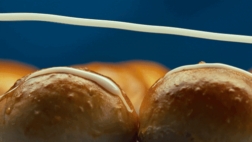 A Close Up Of Two Glazed Doughnuts On A Blue Surface GIF