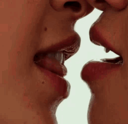 A Close Up Of Two Women Kissing Each Other On The Lips . GIF