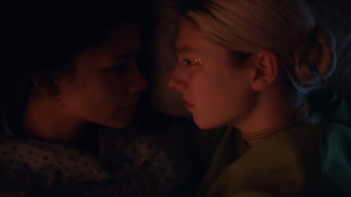 A Close Up Of Two Women Looking At Each Other In A Dark Room GIF