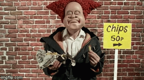 A Clown Is Eating Chips In Front Of A Brick Wall GIF