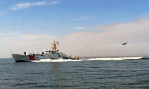 A Coast Guard Ship With A Plane Flying Overhead GIF
