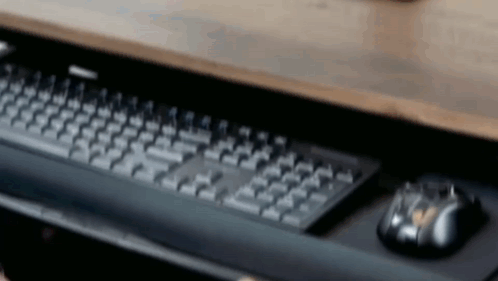 A Computer Keyboard And Mouse Are On A Wooden Desk . GIF