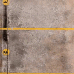 A Concrete Parking Lot With Yellow Lines And Numbers 1 And 2 GIF