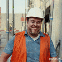 A Construction Worker Wearing An Orange Vest And A White Hard Hat GIF