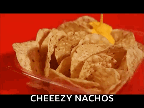 A Container Of Nachos With Cheese Being Poured On Top Of Them . GIF