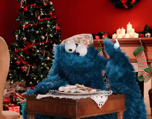 A Cookie Monster Is Sitting At A Table With A Plate Of Cookies GIF