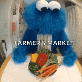 A Cookie Monster Is Sitting At A Table With A Plate Of Vegetables And The Words " Farmer 'S Market " Above It GIF