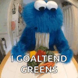 A Cookie Monster Is Sitting On A Table With Vegetables And Says I Goaltend Greens . GIF