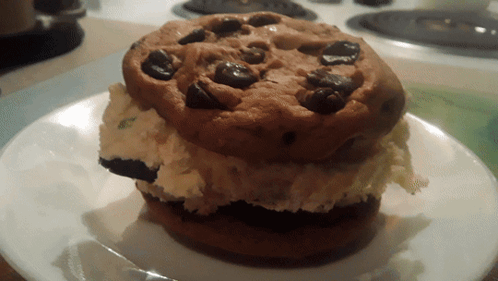 A Cookie With Chocolate Chips On Top Of A White Plate GIF