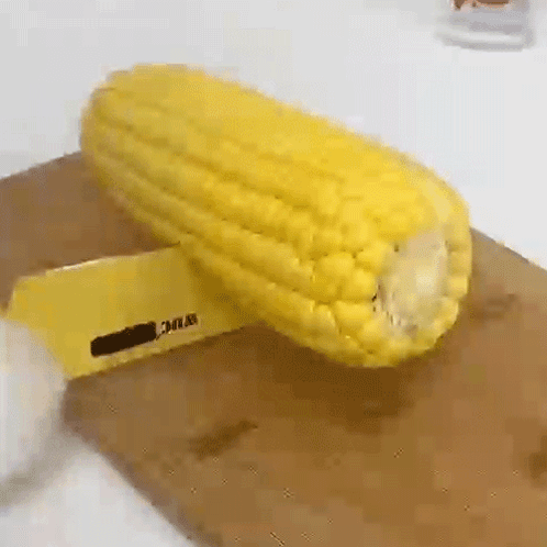 A Corn On The Cob Is Being Peeled On A Cutting Board . GIF